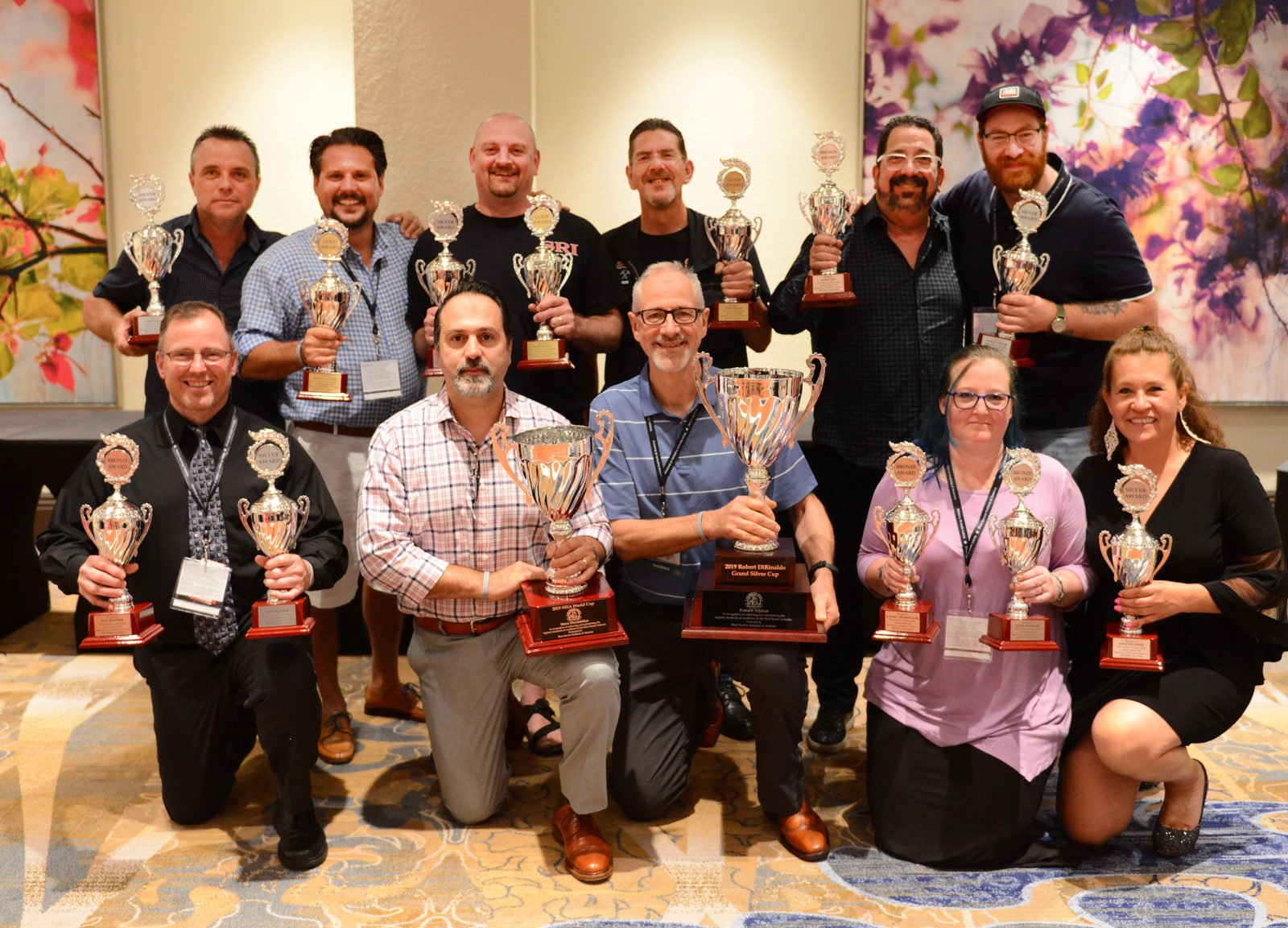 Group of people posing with trophies at an awards ceremony in a conference room.
